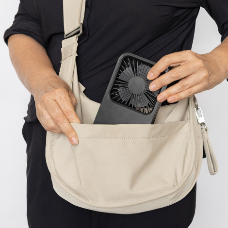 Ventilateur glissé dans un sac porté en bandoulière tenu par une personne, sans marquage apparent