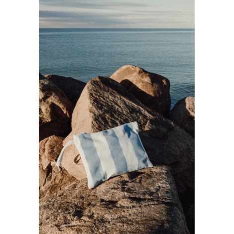 Pochette posée sur des rochers en bord de mer en situation d’usage, sans personnalisation apparente