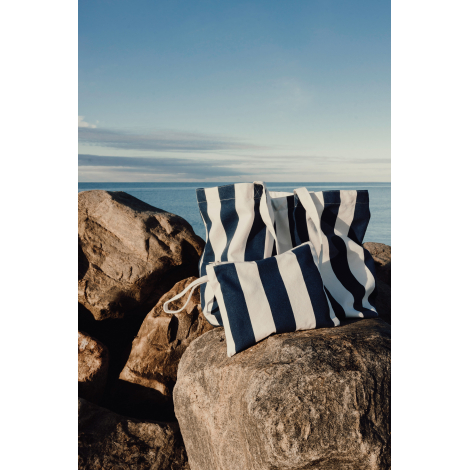 Pochette présentée avec un sac de plage assorti sur des rochers en extérieur, sans marquage visible