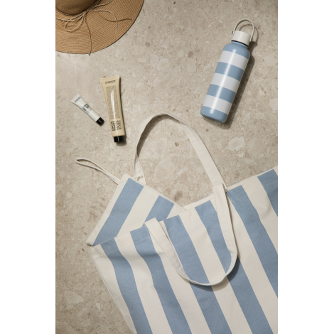 Pochette ouverte avec accessoires de toilette à proximité sur fond clair, sans personnalisation apparente