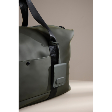 Étiquette bagage attachée à un sac de voyage en situation d’usage, sans marquage visible