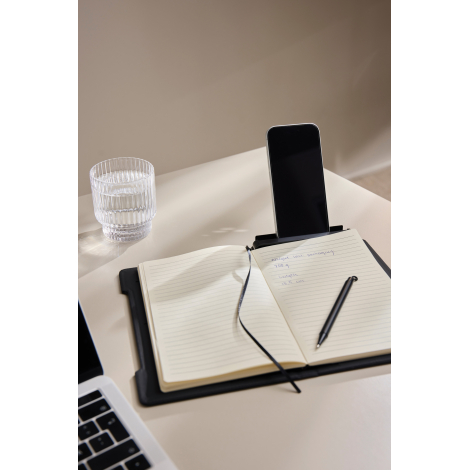 Carnet ouvert en situation d’usage sur un bureau avec smartphone en support et stylo posé, sans marquage visible