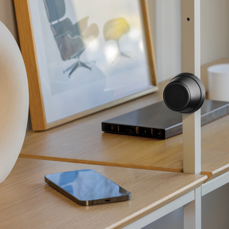 Haut-parleur fixé sur une surface métallique avec smartphone à proximité en situation d’usage, sans personnalisation apparente