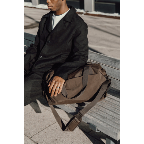 Sac posé à côté d’une personne assise sur un banc en situation d’usage, sans marquage apparent