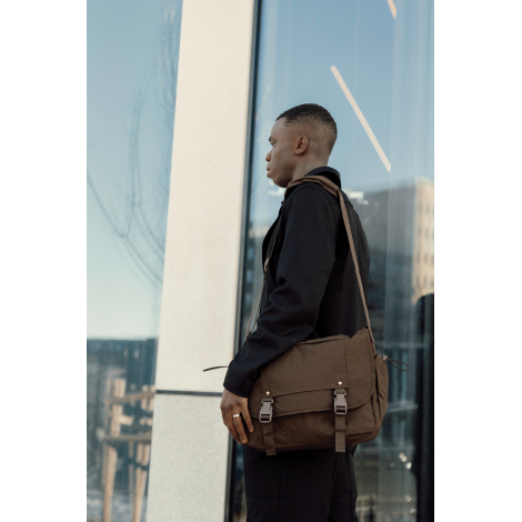 Sac messager porté en bandoulière par un homme en extérieur en situation de déplacement, sans personnalisation visible