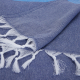 Vue rapprochée d’une serviette bleue pliée, avec franges apparentes.
