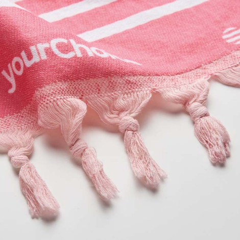 Gros plan sur serviette rose avec franges et marquage texte visible sur le tissu