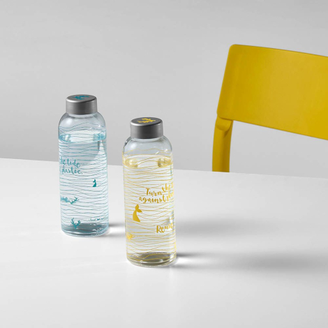 Deux bouteilles en verre transparent avec bouchon gris posées sur une surface, avec marquage visible sur la surface extérieure.