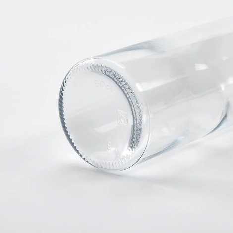 Gros plan du fond d’une bouteille en verre transparente couchée, mettant en avant la base, sans marquage visible.