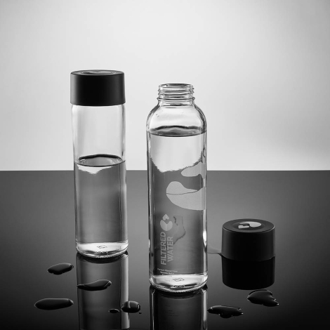 Deux bouteilles en verre dont une ouverte avec bouchon séparé contenant du liquide avec gouttes d’eau sur la surface, avec marqu