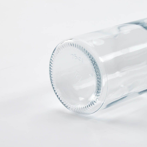 Gros plan du fond d’une bouteille en verre transparente couchée mettant en avant la base, sans personnalisation visible.