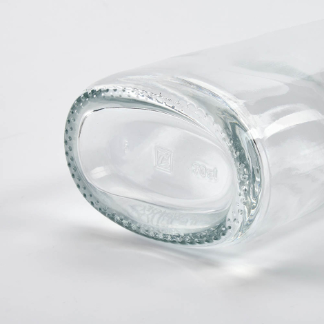 Gros plan du fond d’une bouteille en verre couchée mettant en avant la base, sans marquage visible.