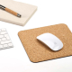 Tapis de souris en liège utilisé sur un bureau avec une souris, un clavier et un carnet à proximité, sans marquage visible.