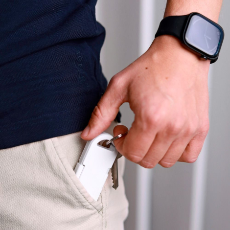 Powerbank blanche partiellement insérée dans une poche tenue en main avec clés attachées, sans marquage visible.