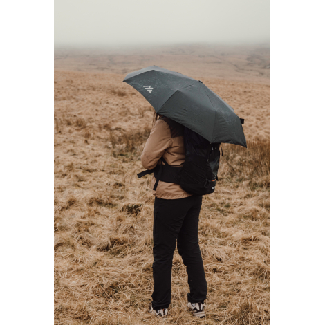 Personne de dos tenant un parapluie ouvert en extérieur avec sac à dos, sans personnalisation visible sur le produit.