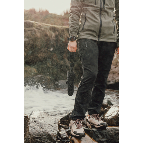 Personne marchant en extérieur tenant un parapluie fermé à la main, sans marquage visible.