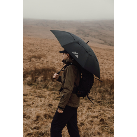 Personne avec sac à dos tenant un parapluie ouvert en extérieur, sans marquage visible sur la toile.