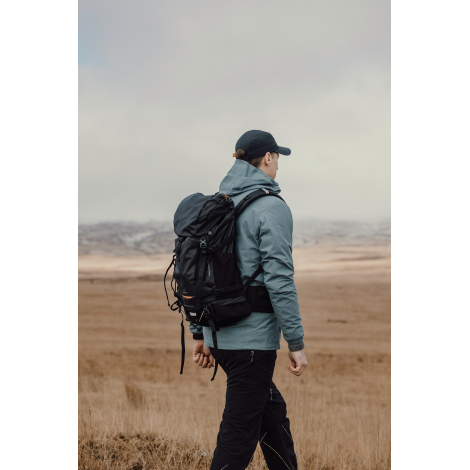 Sac à dos porté par une personne de dos en extérieur, sans personnalisation visible.