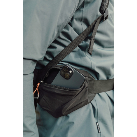 Gros plan sur une poche zippée portée à la taille contenant un objet, sans personnalisation visible.