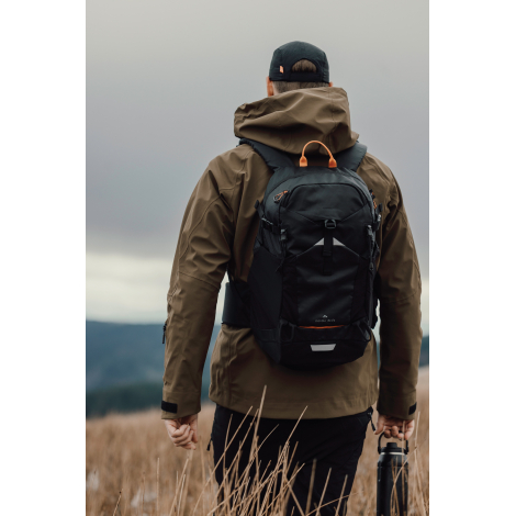 Sac à dos porté par une personne de dos en extérieur, sans personnalisation visible.