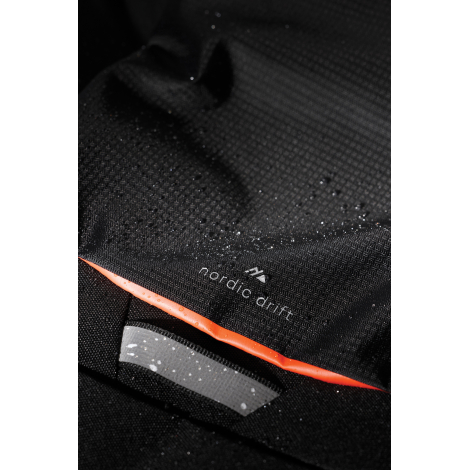 Gros plan sur la matière du sac avec gouttes d’eau et éléments graphiques, sans marquage visible.