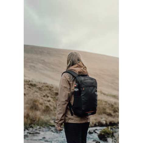 Sac à dos porté par une personne en extérieur vu de dos, sans personnalisation visible.