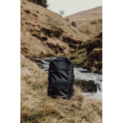 Sac à dos posé en extérieur près d’un cours d’eau, sans marquage visible.