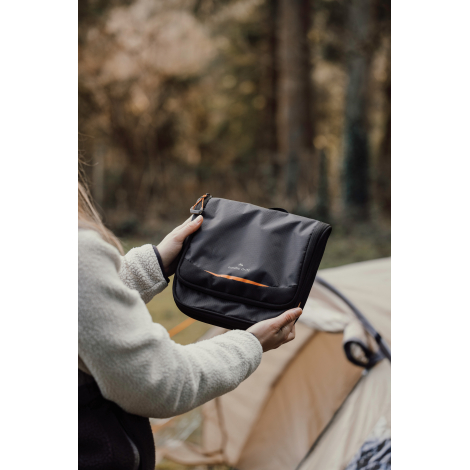 Personne tenant la trousse fermée en extérieur, sans marquage apparent.