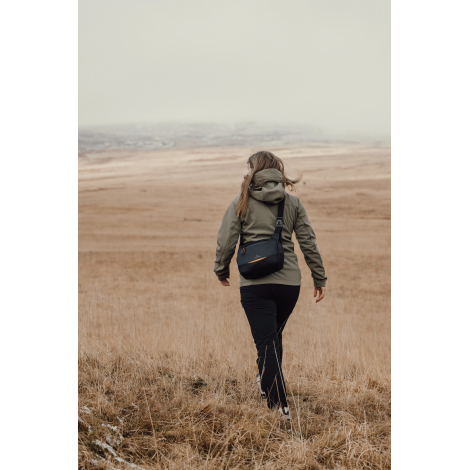 Personne marchant en extérieur avec sac bandoulière porté dans le dos, sans marquage visible.