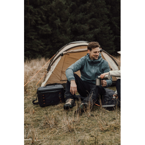 Deux personnes en extérieur avec sac isotherme posé au sol, sans personnalisation visible.