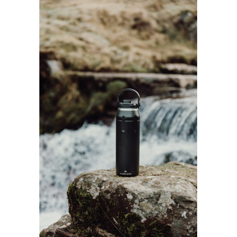 Bouteille posée sur un rocher en extérieur, sans personnalisation visible.