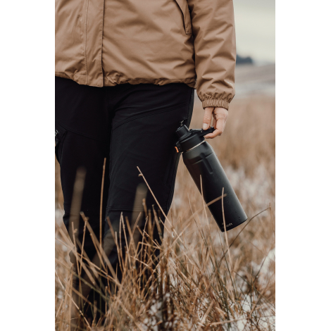 Personne tenant une gourde à la main en extérieur, sans personnalisation visible.