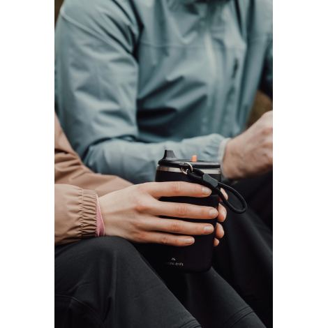 Personne tenant un gobelet assise en extérieur, sans personnalisation visible.