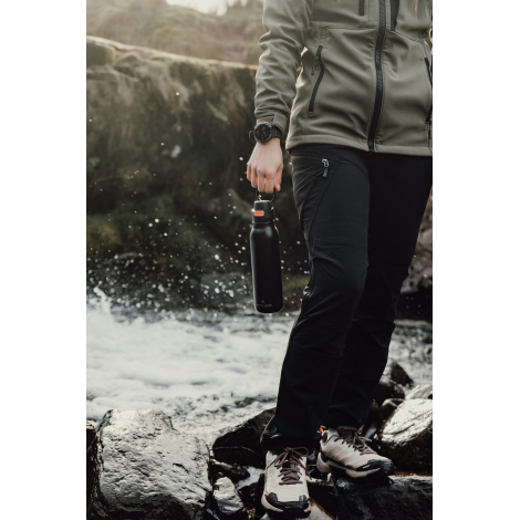 Personne marchant en extérieur tenant une gourde à la main, sans marquage visible.