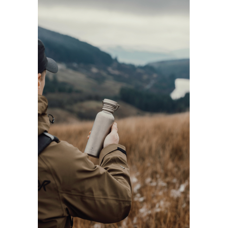 Personne tenant une gourde en extérieur, sans marquage visible.
