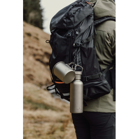 Gourde accrochée à un sac à dos en extérieur, sans personnalisation visible.