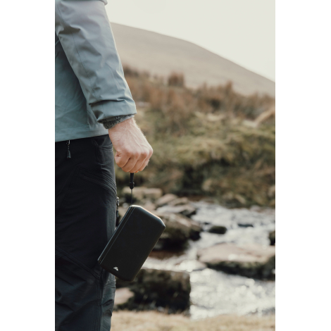 Personne tenant une powerbank à la main en extérieur, sans personnalisation visible.