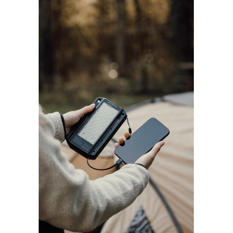 Personne utilisant une powerbank pour charger un téléphone, sans marquage visible.