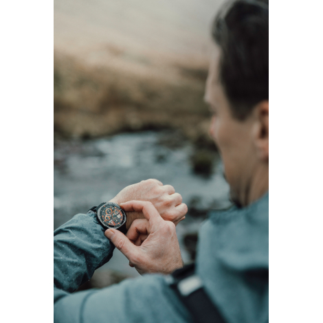 Montre connectée portée au poignet d’un homme manipulant l’écran en extérieur, sans personnalisation visible.
