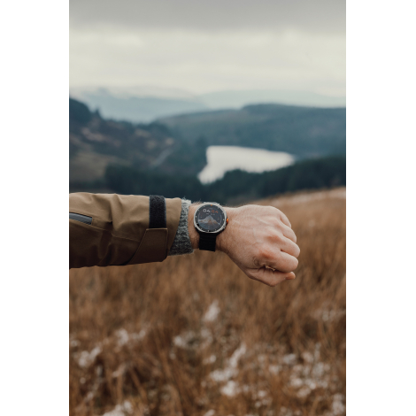 Montre connectée portée au poignet en extérieur avec paysage, affichage de l’heure, sans marquage visible.