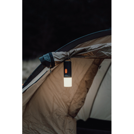 Lampe de camping suspendue à une tente en extérieur avec éclairage allumé, sans marquage visible.