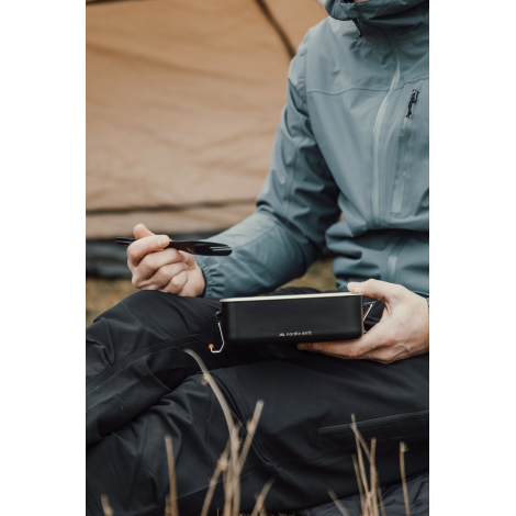 Personne utilisant le set de couverts en extérieur en tenant un récipient, sans personnalisation visible.