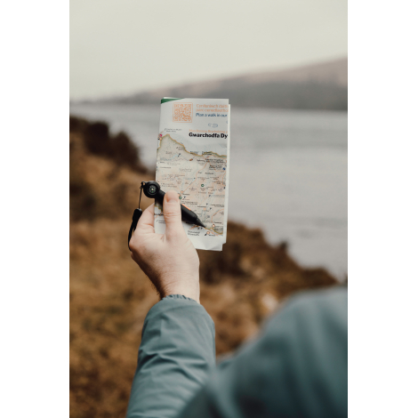 Crayon infini tenu en main au-dessus d’une carte en extérieur, sans personnalisation visible.