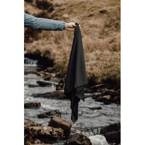 Serviette tenue à la main au-dessus d’un cours d’eau en extérieur, sans personnalisation visible.