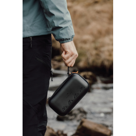 Étui rigide tenu à la main en extérieur, sans marquage apparent.