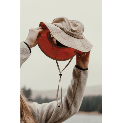 Bob beige tenu en main montrant intérieur avec cordon de serrage, sans marquage visible.