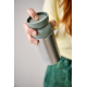 Personne tenant un mug isotherme avec partie supérieure verte, sans personnalisation visible sur la zone du produit visible.