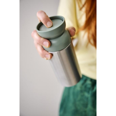 Personne tenant un mug isotherme avec partie supérieure verte, sans personnalisation visible sur la zone du produit visible.
