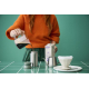 Mug isotherme utilisé sur une table avec accessoires de boisson, sans marquage visible.
