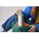 Personne tenant un mug isotherme avec partie supérieure verte partiellement dans un sac, sans personnalisation visible sur la zo